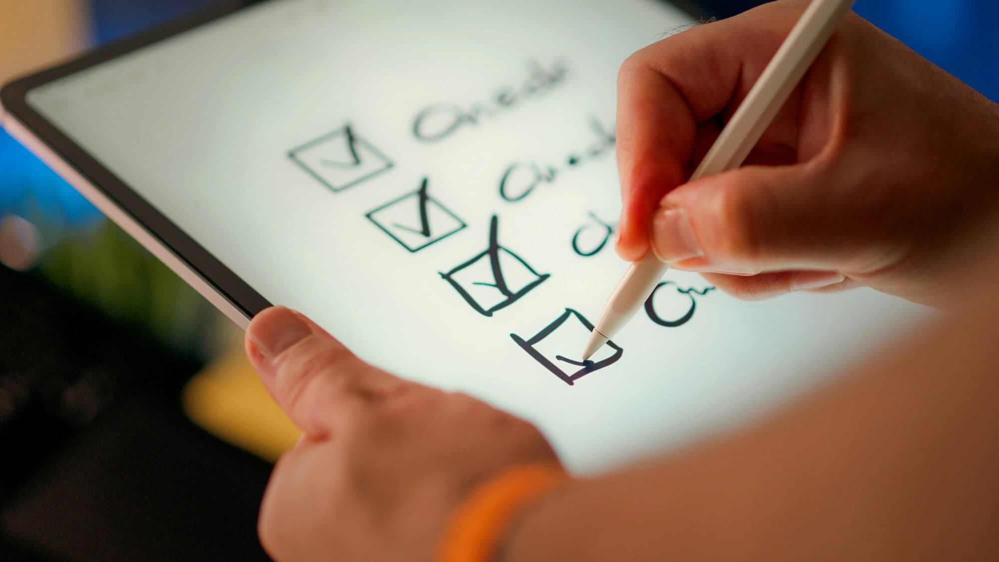 A hand checking off items on a digital tablet checklist